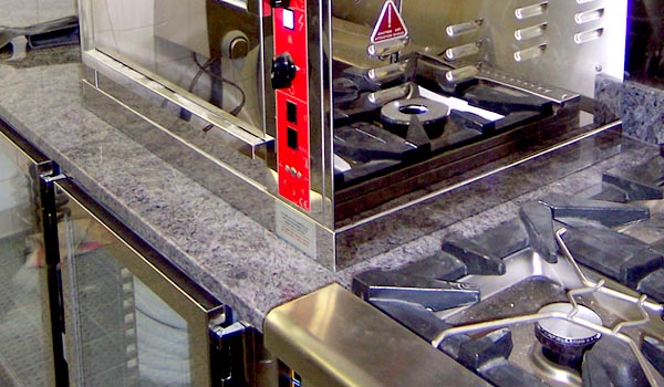 <b>FAUCHON</b> - 30, place de La Madeleine - Paris VIIIe<br/><br/>Rôtissoire sur plan de travail granit ajusté à la ligne de cuisson.<br/>Meuble bas réfrigéré ACTIF, avec portes vitrées et groupe froid à distance.