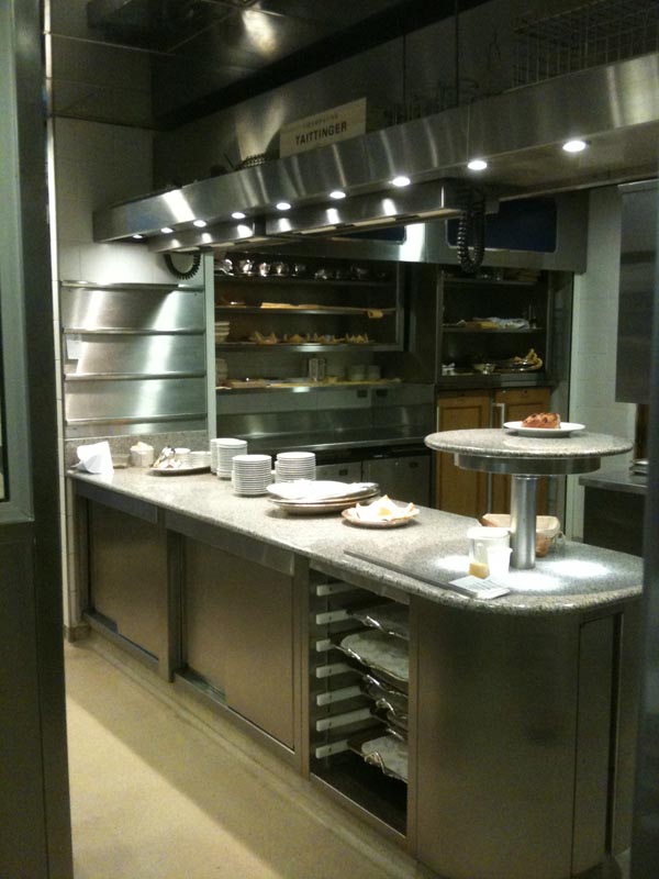 <b>LA TOUR D'ARGENT</b> - 15, quai de la Tournelle - Paris Ve<br/><br/>Zone d'envoi : plateau granit sur meuble traversant chauffe-assiettes.<br/>Passe chaud avec céramiques ajustables en hauteur.  Office bar en arrière-plan